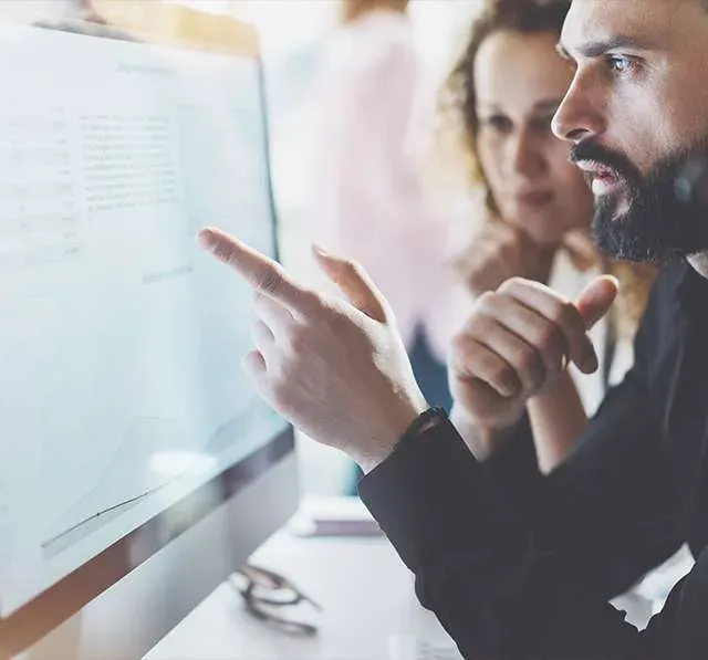 Due colleghi che discutono davanti a uno schermo in ufficio