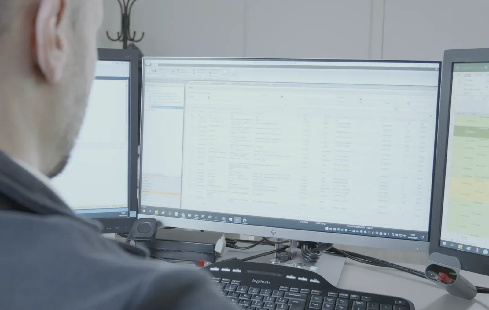 Un operatore di spalle davanti a tre monitor con la schermata di avanzamento della produzione